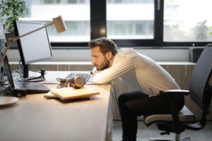 Stress, homem debruçado sobre a secretaria a sofrer devido ao stress.